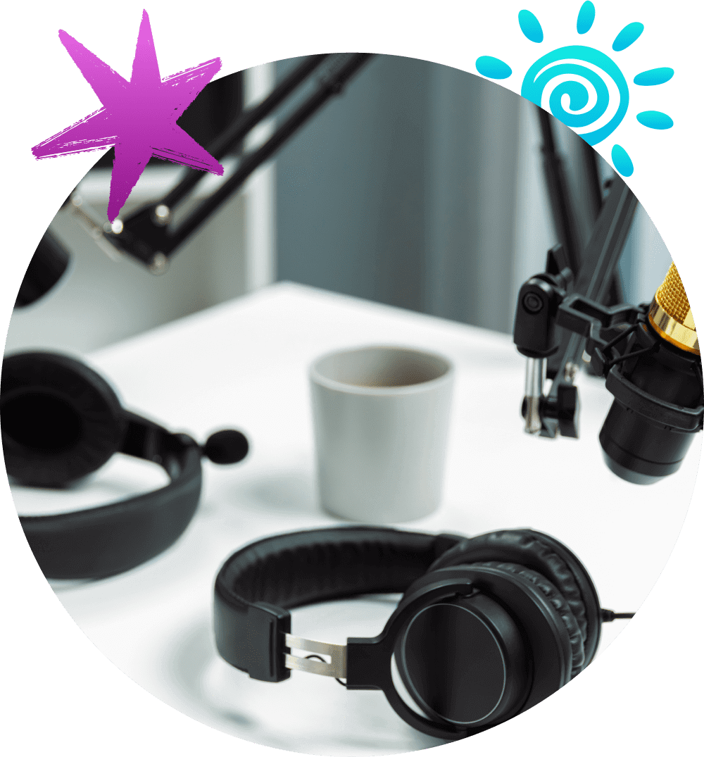 Headphones, coffee cup, and microphone on a desk.